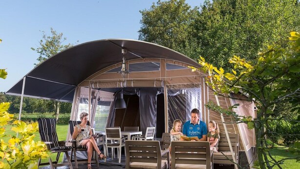 A covered outdoor seating area with chairs and tables, a tent-like structure, and a staircase leading to an upper level.