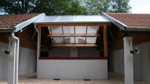 A covered outdoor seating area with a brick floor and a metal roof.