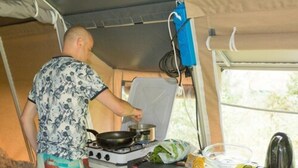 A compact kitchen with a portable stove, a sink, and a window providing natural light.