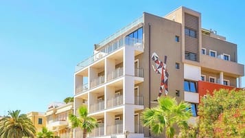 Un edificio a più piani con balconi, un murale geometrico e palme.