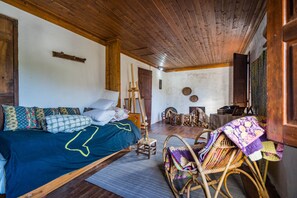 A cozy room with a wooden ceiling, a bed with patterned bedding, a small stool, and wicker furniture. - Beautiful country house in Monte Vale Grande. Very quiet rural area. (Soure)