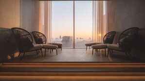 Un intérieur moderne avec de grandes fenêtres, deux fauteuils en osier noir et un plancher en bois.