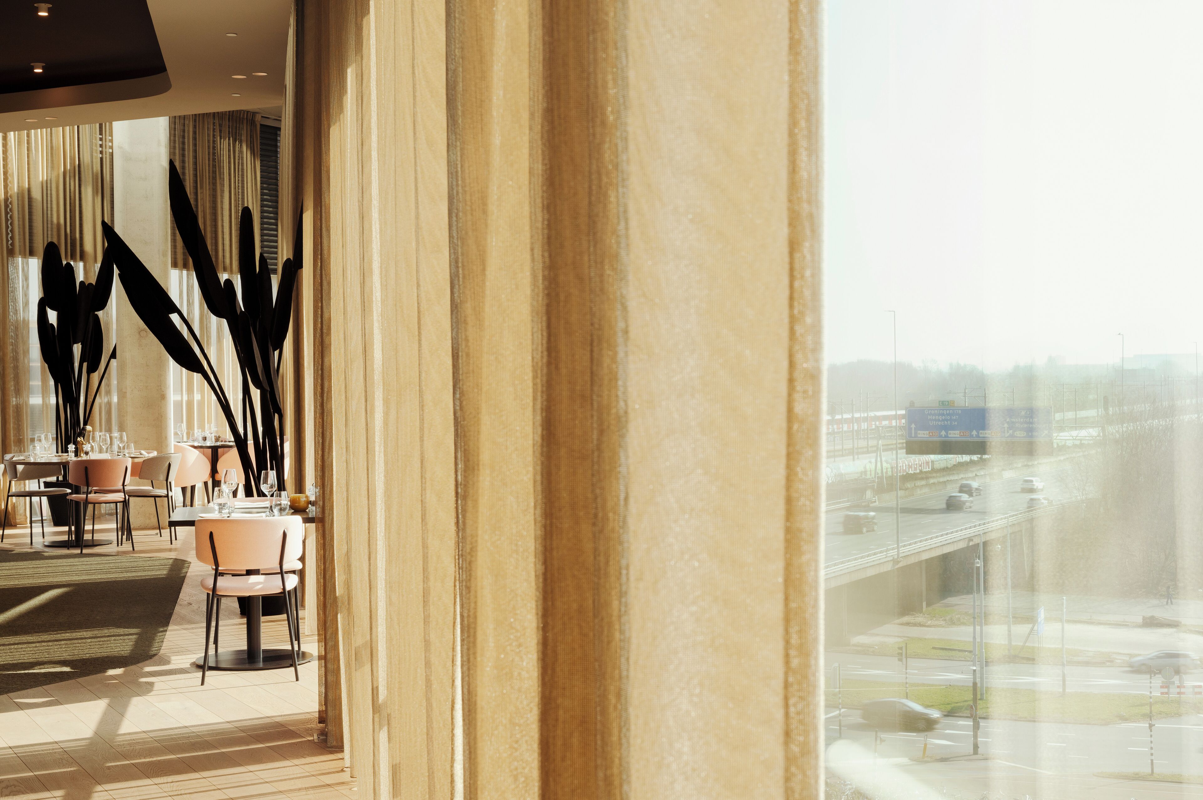 A modern hotel lobby with a large window overlooking a highway.