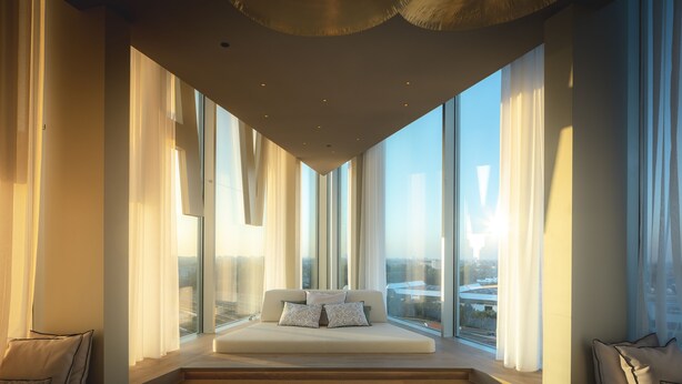 Une chambre moderne dotée d’une grande fenêtre, d’un canapé-lit et offrant une vue sur le paysage urbain.