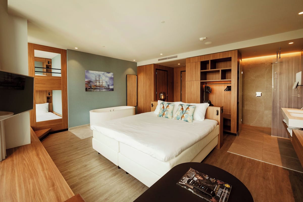 Een moderne hotelkamer met een groot bed, een houten garderobe, een televisie en een klein tafeltje.