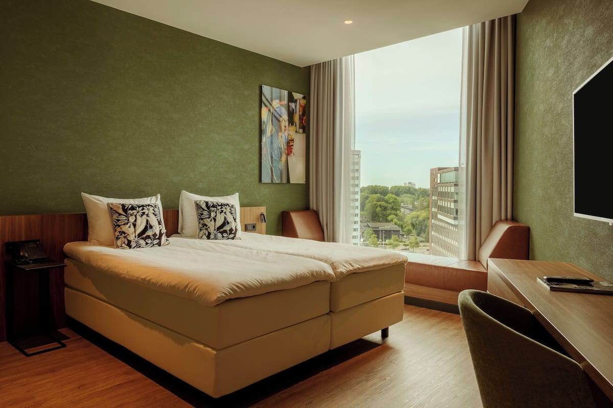 Een hotelkamer met een groot bed, een bureau en uitzicht op de stad.