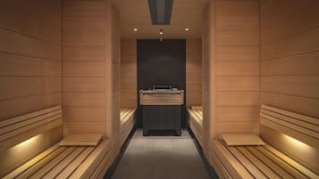 A sauna with wooden benches and a central table, featuring a modern design and recessed lighting.