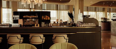 A bar area with a modern design, featuring a bar counter, seating, and a coffee machine.