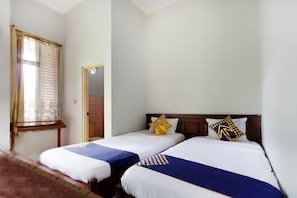 A hotel room with two single beds, a window with curtains, a wooden headboard, and a door. - SPOT ON 2730 Hotel Maribaya Indah Syariah (Cisayong)