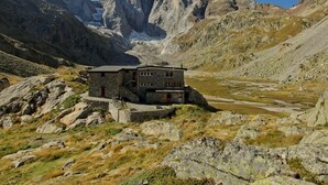 Un bâtiment en pierre doté d’un toit plat, situé dans une région montagneuse caractérisée par un terrain rocheux et une vallée.