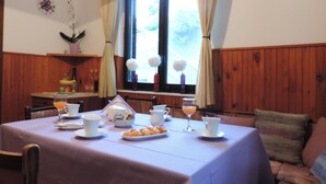 A dining area with a table set for two, featuring a white tablecloth, plates, cups, and a glass of orange juice. - Apartments Vodnica (Dubrovnik)