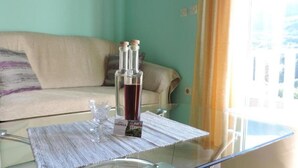A glass table with a bottle of water and a glass, a glass tablecloth, and a sofa in the background. - Apartments Vodnica (Dubrovnik)