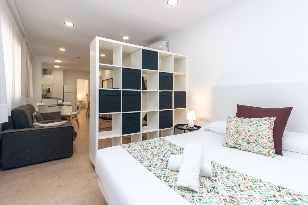 Ein modernes Hotelzimmer mit einem großen Bett, einer Sitzecke, einem Schreibtisch und einem integrierten Stauraum.