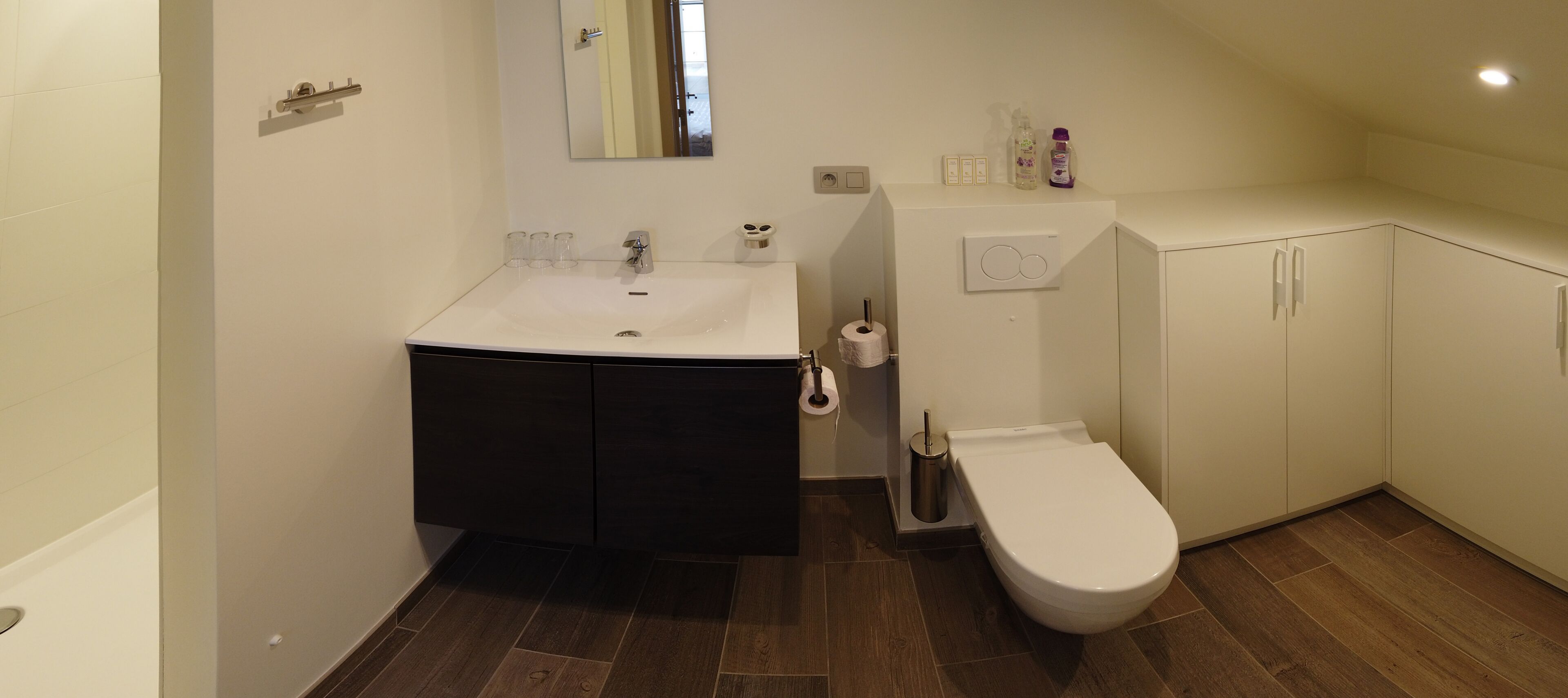 A bathroom with a white sink, dark cabinets, a white toilet, and a mirror.