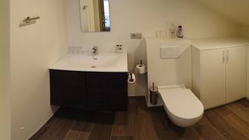 A bathroom with a white sink, dark cabinets, a white toilet, and a mirror.