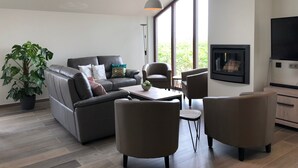 Un salon moderne avec un canapé, des fauteuils, une table basse et un téléviseur.