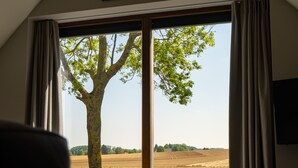 Une chambre avec une grande fenêtre, un lit et un tableau accroché au mur.