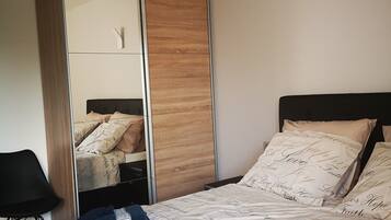 Een slaapkamer met een bed, een kledingkast en een nachtkastje.