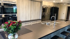 Une cuisine moderne dotée d’appareils électroménagers en acier inoxydable, d’un îlot central avec un évier et d’un vase de fleurs.