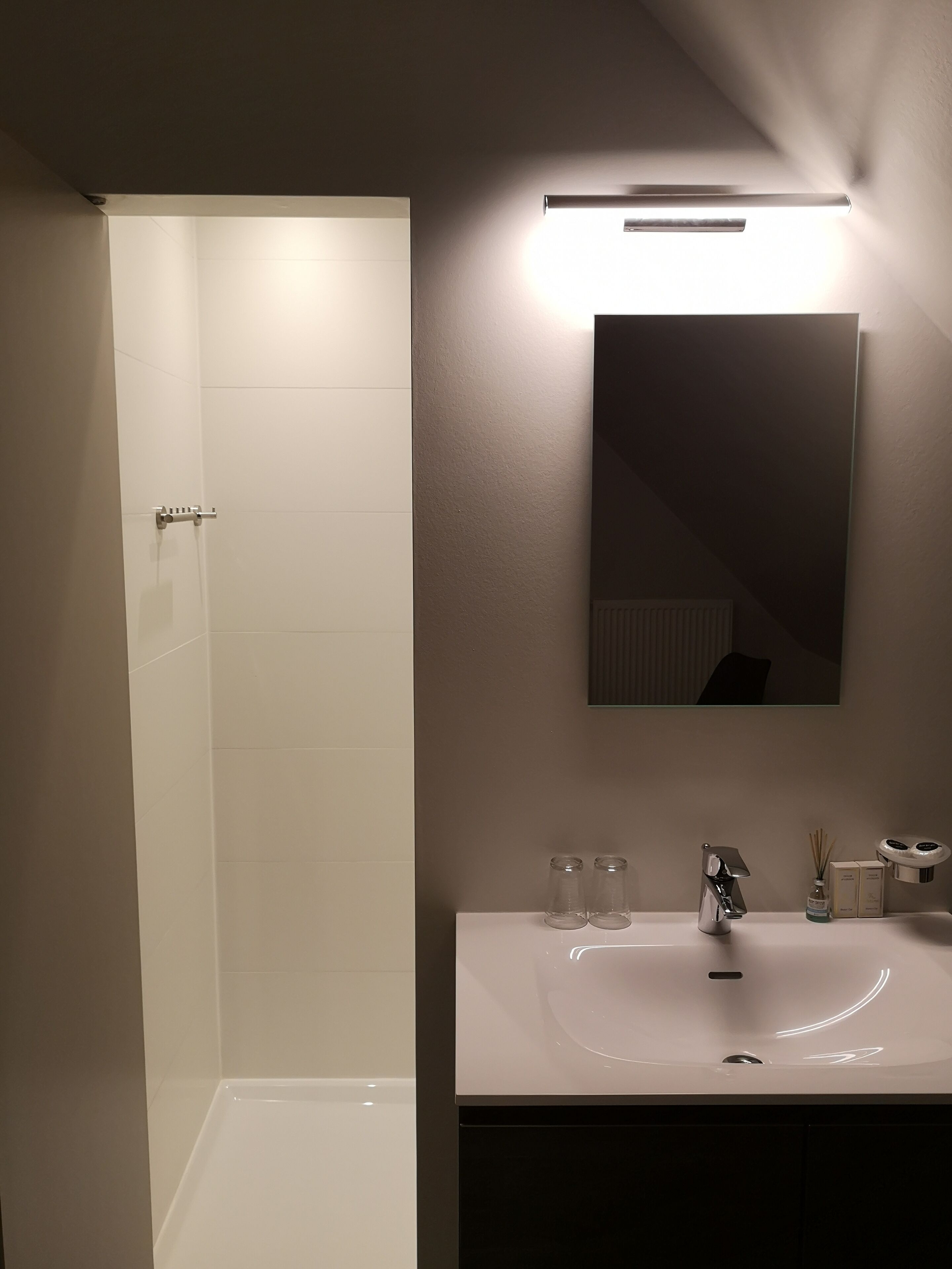 Et moderne badeværelse med en hvid vask, et spejl og en brusezone.