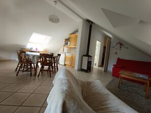 A loft-style living space with a dining area, kitchen, and a red couch.
