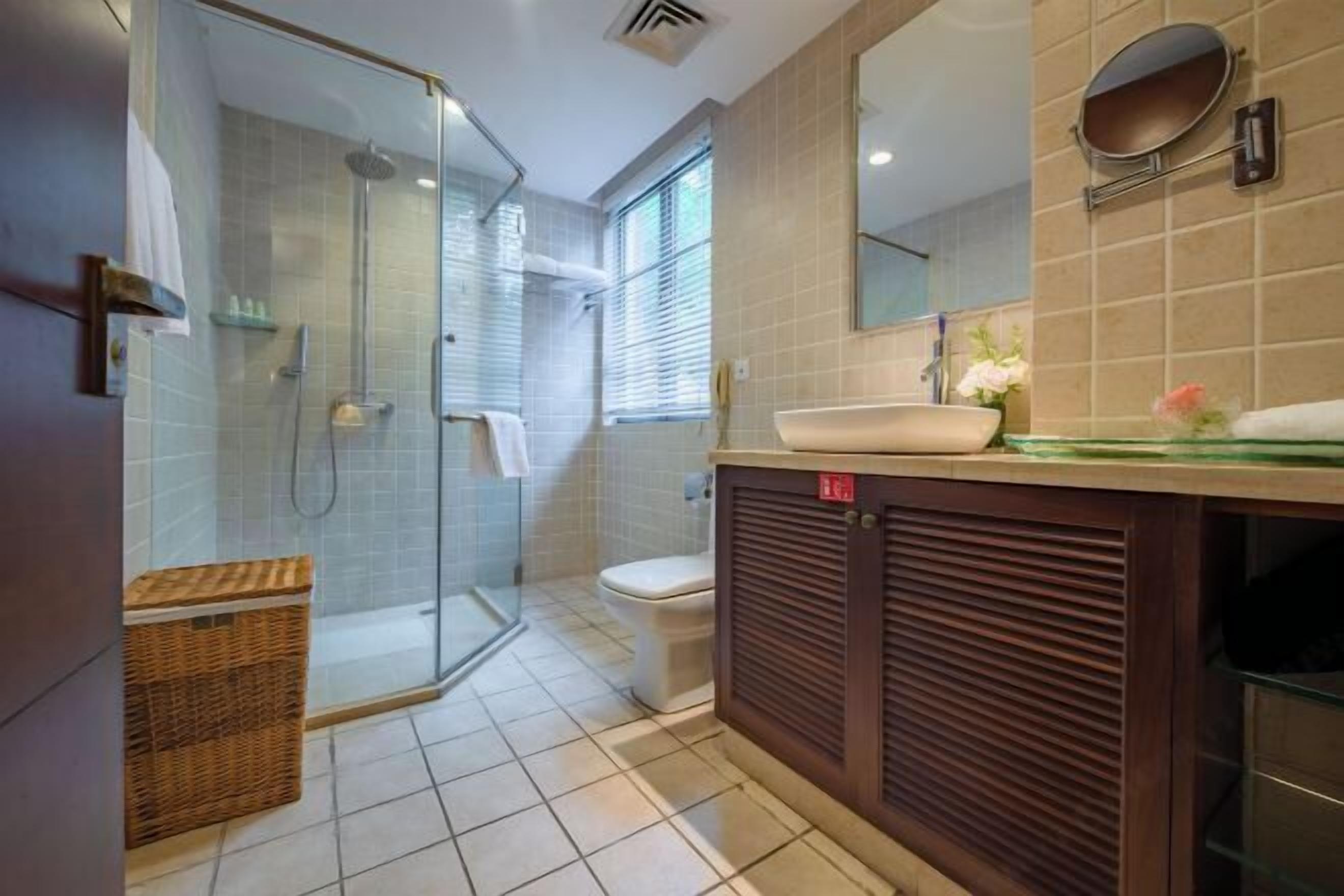 Une salle de bain moderne avec une douche à parois de verre, des toilettes, un lavabo avec un miroir et un panier en osier.