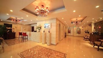 A spacious lobby with a reception desk, seating area, and decorative lighting.
