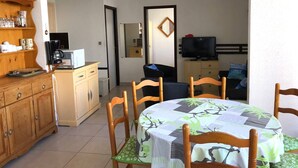 Un espace de vie compact comprenant un coin repas, une kitchenette et un téléviseur.