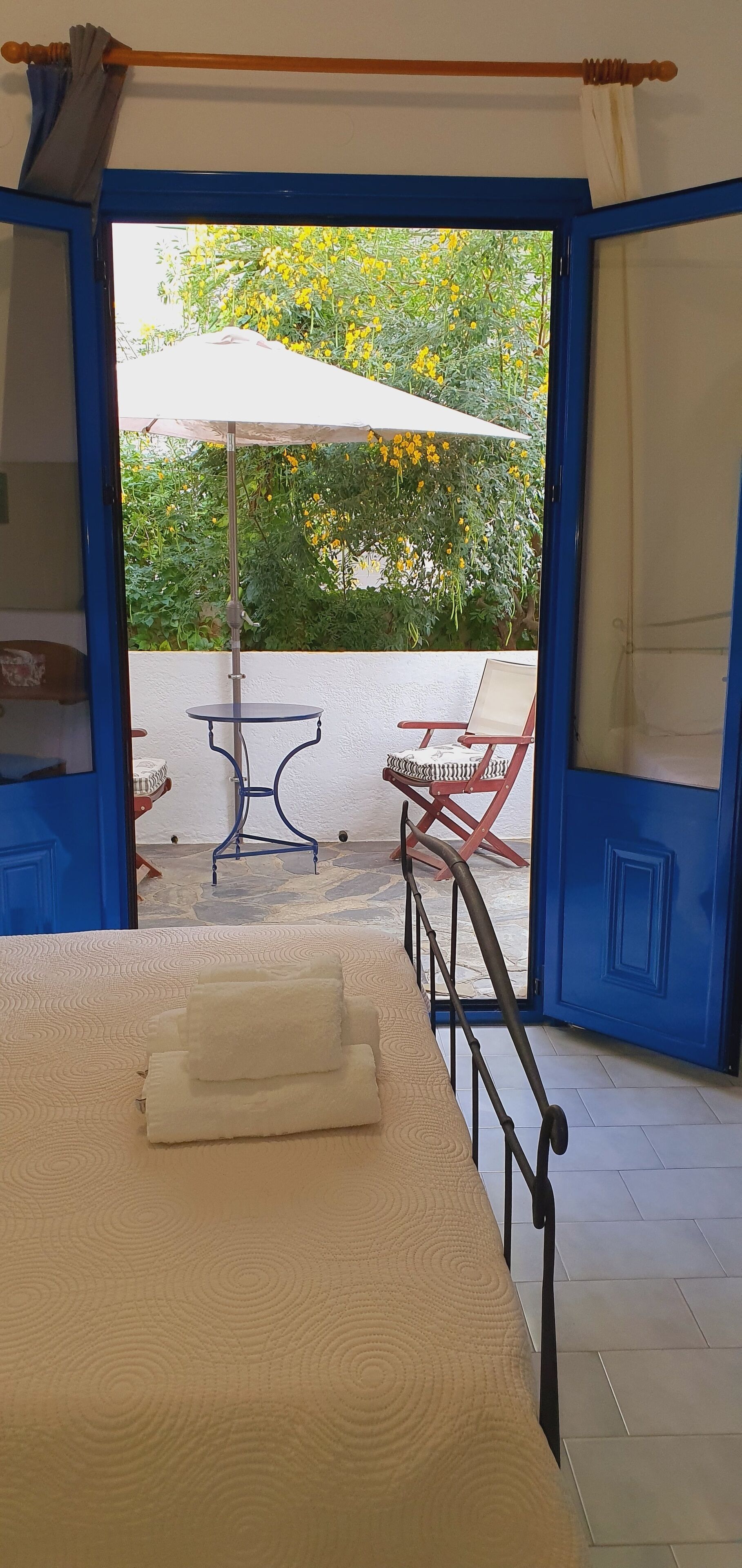A room with a bed, a table, and chairs outside a blue door.