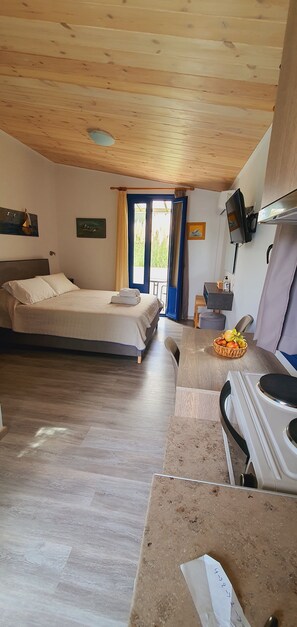 Una habitación con una cama, un escritorio con computadora, un televisor y una ventana con cortinas.