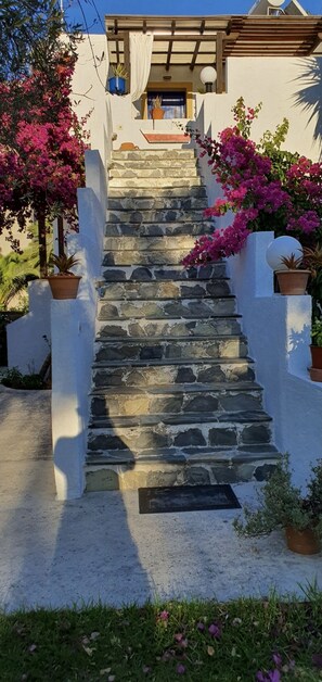 A stone staircase leading to a white building with potted plants and flowers. - Irini Studios (Apokoronas)