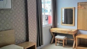 A room with a bed, a desk, a chair, a mirror, and a window with curtains. - Residence 21 Boutique Inn (Miri)
