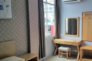 Una habitación con cama, escritorio, silla, espejo y ventana con cortinas.