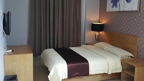 A hotel room with a bed, a desk, a lamp, and a painting on the wall. - Residence 21 Boutique Inn (Miri)