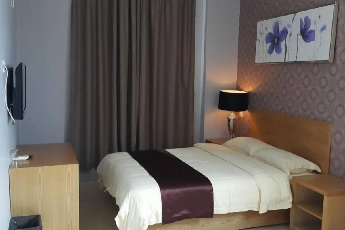 Una habitación de hotel con una cama, un escritorio, una lámpara y un cuadro en la pared.