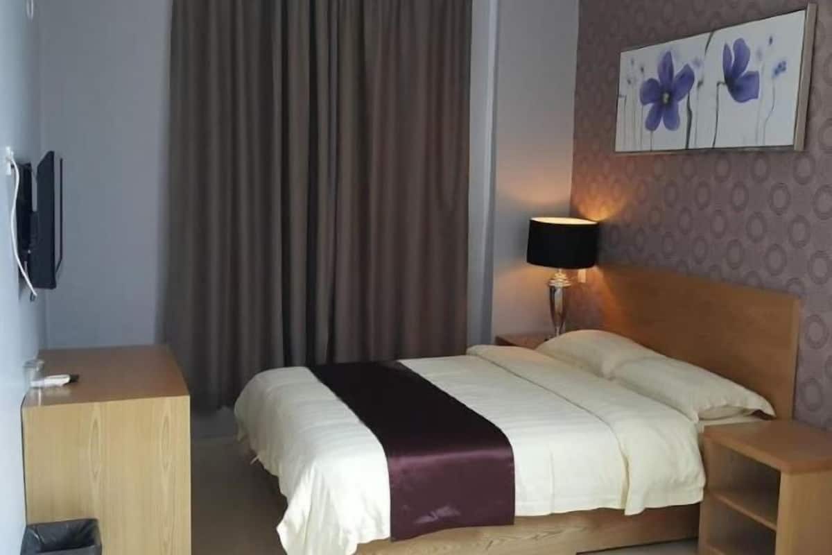 Una camera d'albergo con un letto, una scrivania, una lampada e un quadro appeso al muro.