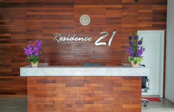 A reception desk with a wooden wall background and the text "Residence 21". - Residence 21 Boutique Inn (Miri)