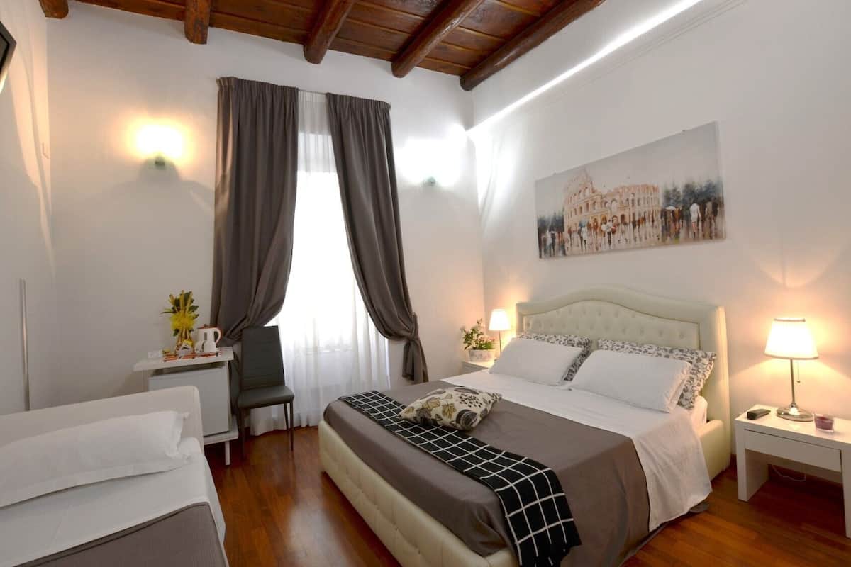 A hotel room with a bed, a desk, a chair, a nightstand, and a painting on the wall.
