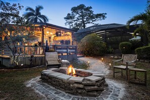 A patio area with a fire pit, seating, and a covered outdoor space with a bar. - Private Hideaway, Pool,  Epic Tiki Bar and close to USSSA! (Melbourne)