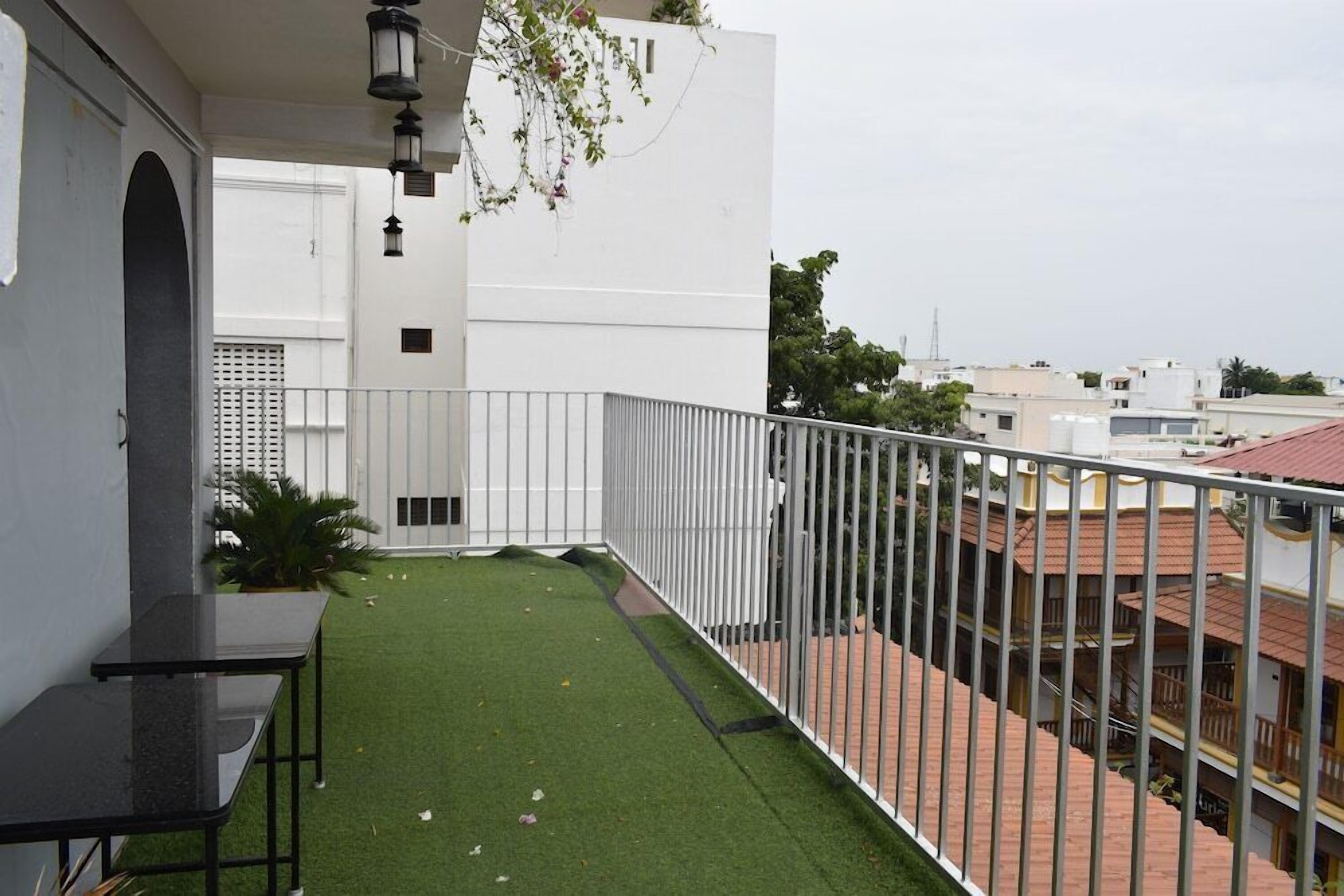 Un balcón con césped artificial, baranda metálica y vistas a edificios vecinos.