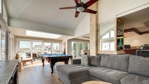 A spacious living room with a pool table, a grey sectional sofa, and a ceiling fan. - Luxurious Channel Islands Harbor Home w/ Boat Dock (Oxnard)