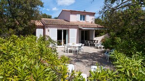 A two-story house with a tiled roof, a patio with outdoor furniture, and a garden with various plants. - 3 bedroom house near Santa Giulia beach Residence heated swimming pool (Porto-Vecchio)