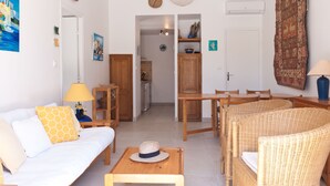 A cozy living room with a sofa, wicker chairs, a dining table, and a kitchen in the background. - 3 bedroom house near Santa Giulia beach Residence heated swimming pool (Porto-Vecchio)
