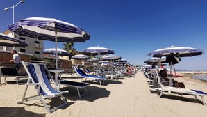 A beachside hotel with rows of sun loungers and umbrellas, a clear sky, and a sandy beach. - Hotel Calgary (Casalbordino)
