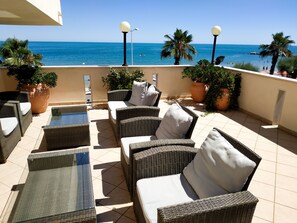 A terrace with wicker furniture, potted plants, and a view of the sea. - Hotel Calgary (Casalbordino)
