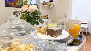 Una mesa de buffet con diversos postres, un vaso de jugo de naranja y un arreglo floral.
