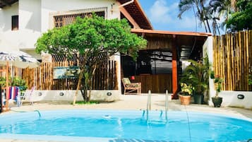 Una piscina al aire libre, sombrillas, sillones reclinables de piscina