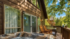 A hot tub on a wooden deck with a view of a forest.