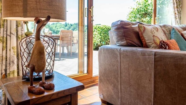 A living room with a sofa, a decorative bird sculpture, and a lamp. - The Dinney Holiday Cottages (Bridgnorth)