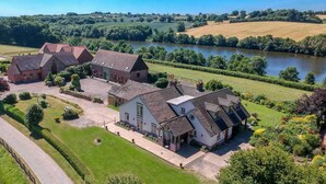 A large estate with multiple buildings, a well-maintained lawn, and a river in the background. - The Dinney Holiday Cottages (Bridgnorth)
